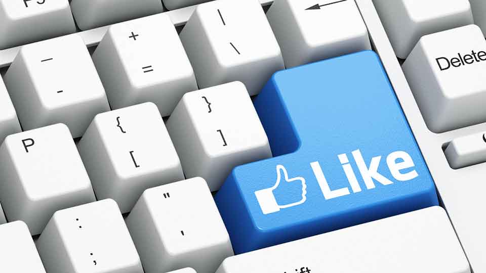 Stock image of a keyboard zoomed in on the enter button which is blue with a thumbs up and 'like' slogan to represent Facebook.