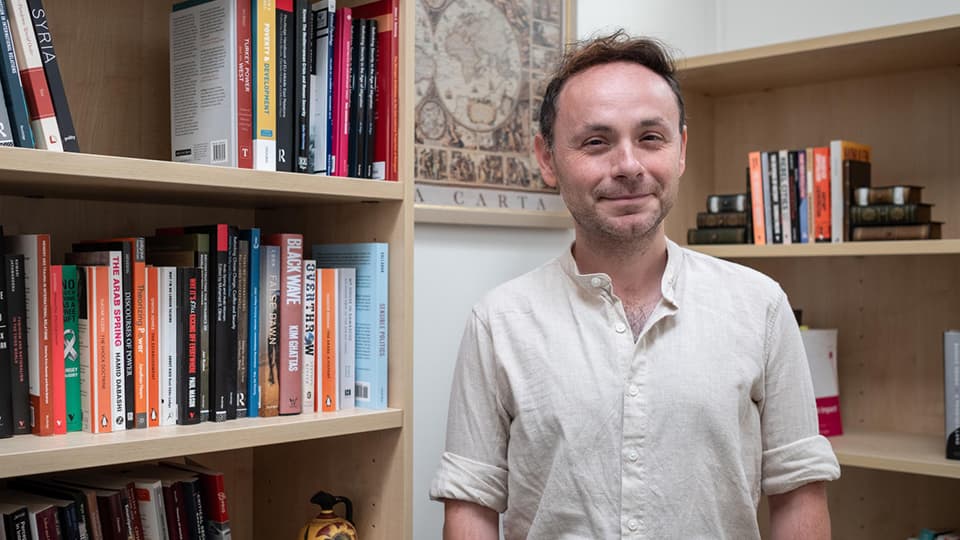 Ali stood in front of a bookcase