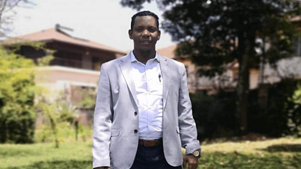 Student in a suit jacket standing in front of greenery