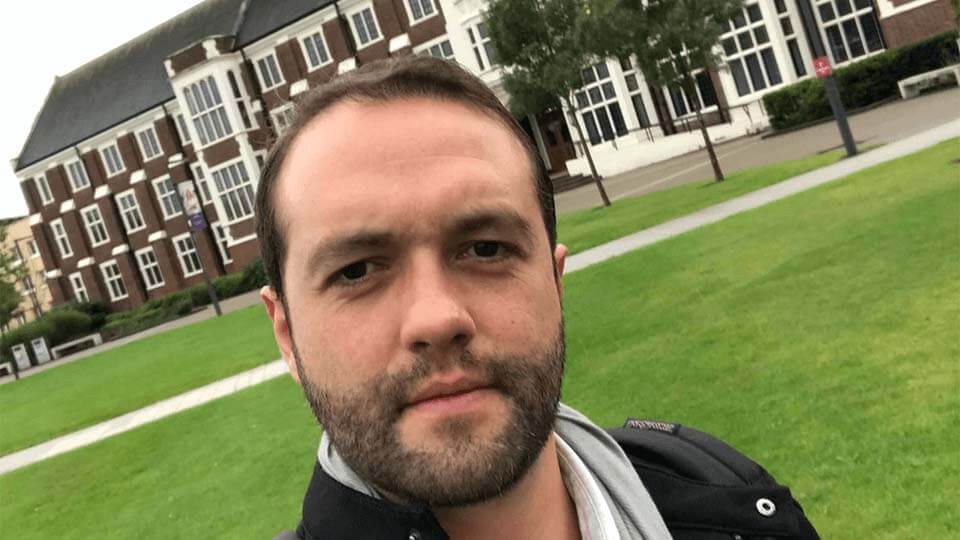 Self-shot image of a student with the Loughborough University main building in the background