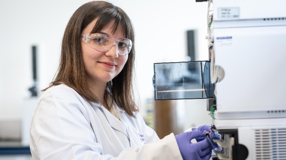 Chemistry student working in a lab and wearing a lab coat.