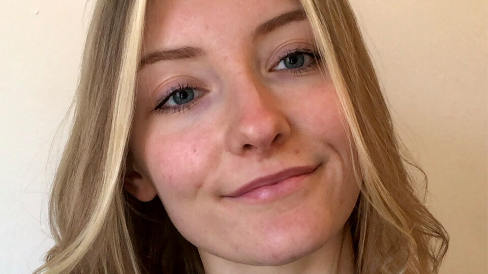 Female student smiling at the camera on a sunny day.