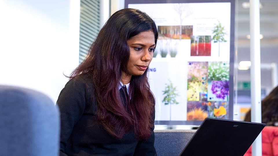 Swetha sitting at a laptop.