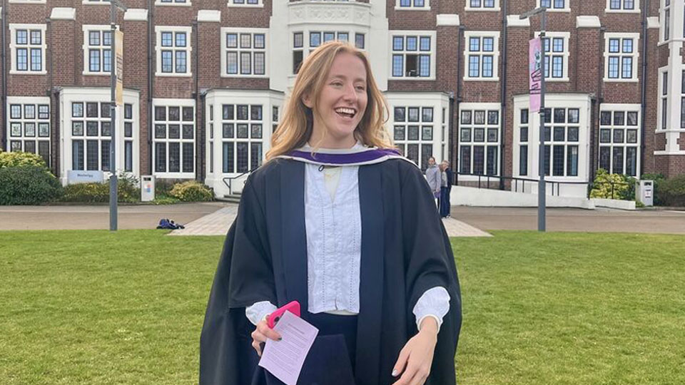 A student smiling outside a building