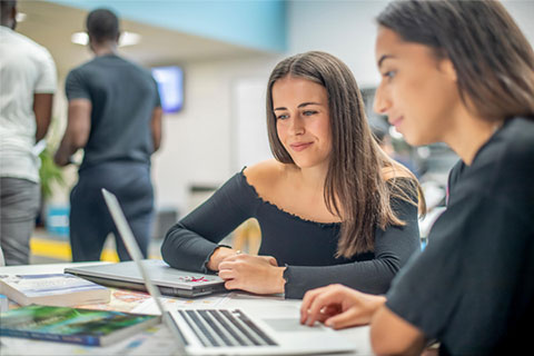 Two female students looking at a laptop screen