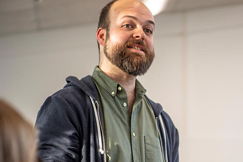 A male lecturer standing speaking to a group of students