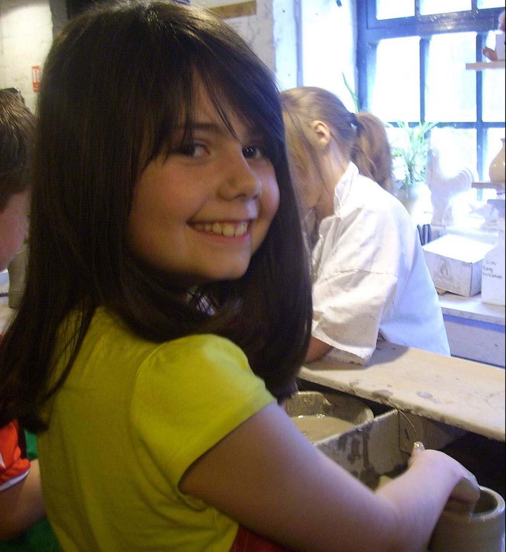 Emma as a child making a pot from clay. 