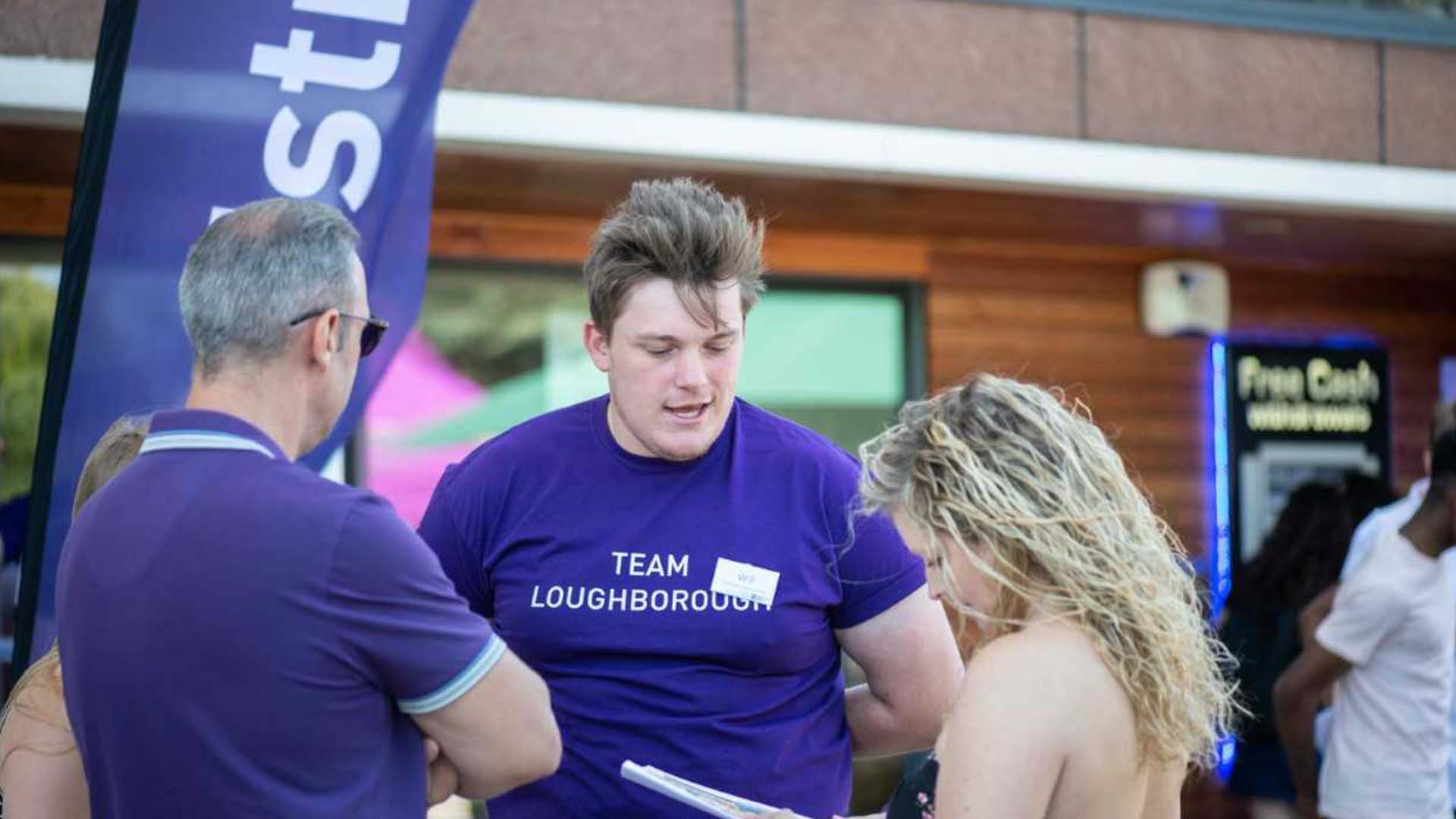 A Student Ambassador talking to visitors at a Loughborough University open day.
