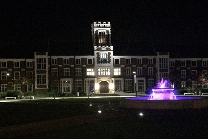 Photo of Hazlerigg at night with the fountain lit up in purple. 