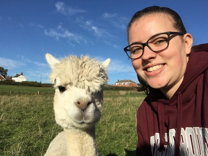 Selfie of Leah and an alpaca in a field. 