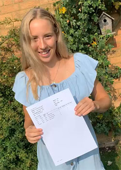 Photograph of Lilly holding a piece of paper with her results printed on it. 