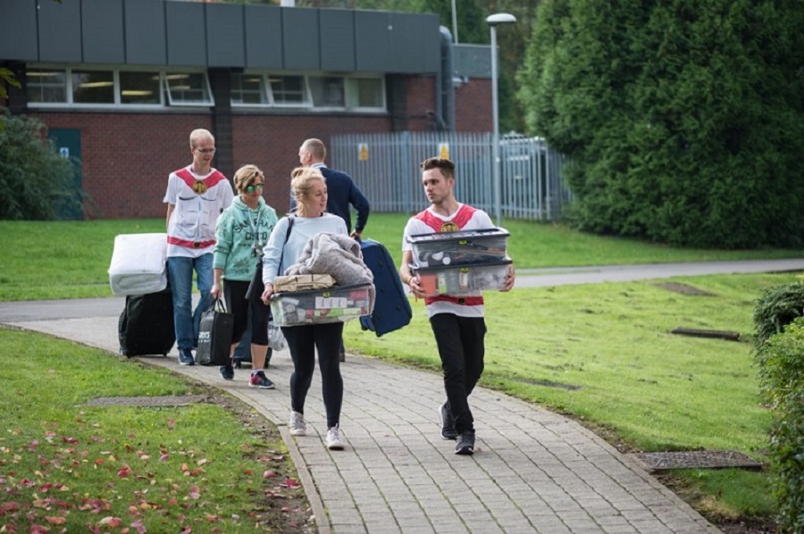 Image of a first year moving into Loughborough University Accommodation with two fresher helpers helping to carry their belongings. 