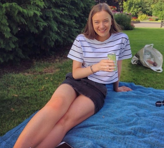 Photo of Eleanor sitting on a picnic blanket in a park. 