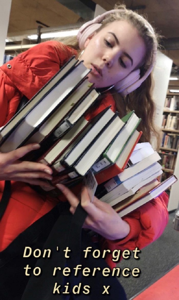 Caroline with her hands full of books in the library with writing on the photo 'Don't forget to reference kids x'. 