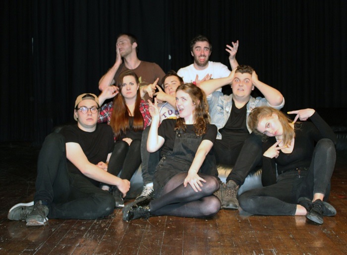 Caroline and seven friends from second year posing for the photo in front of a black background. 