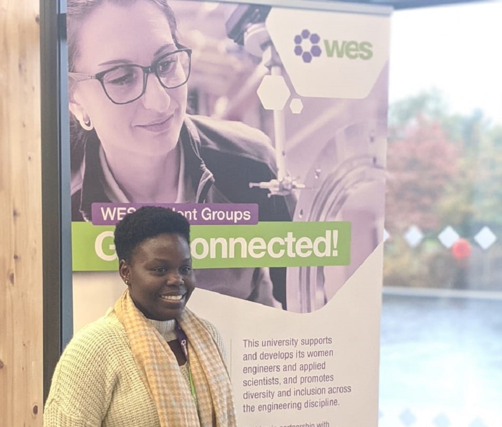 Seyi at the WES Student Conference in front of a WES banner. 