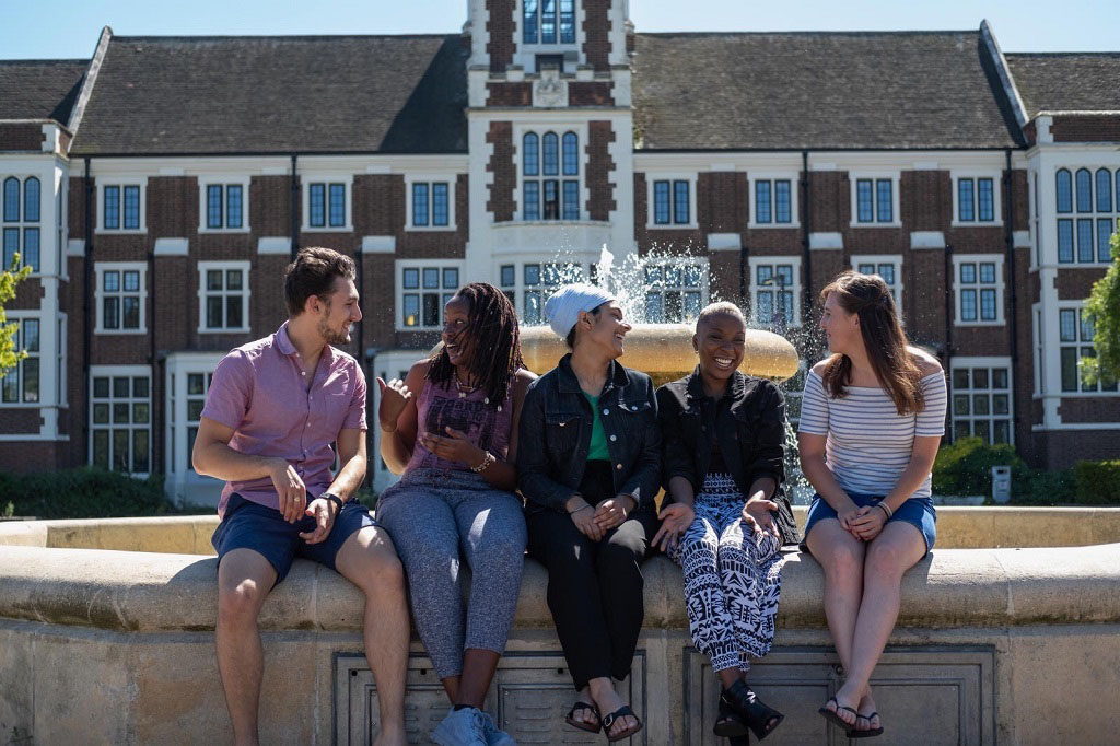 Gugundeep sitting at the university fountain with four friends.  