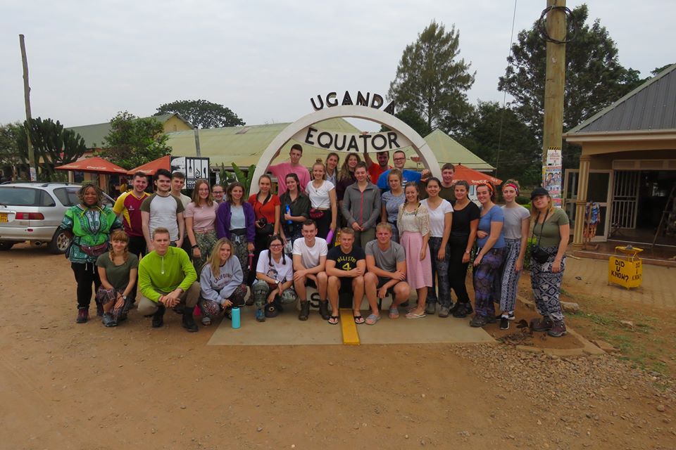 Jess and other university students standing in front of a Uganda sign. 