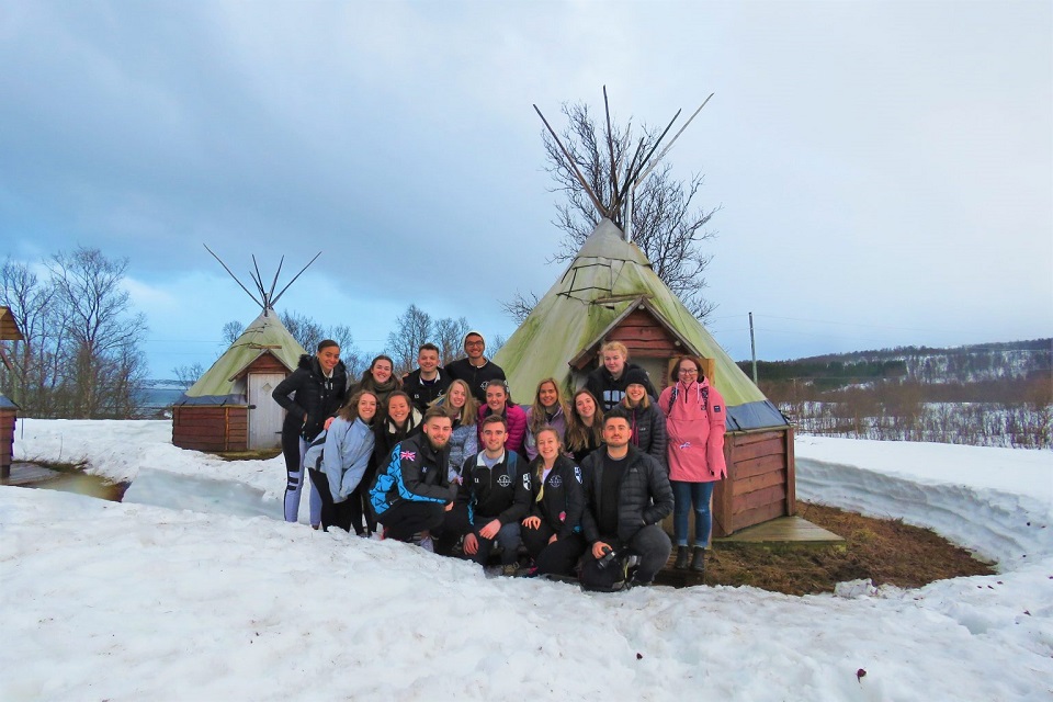 Jess with other university students on the dog sledding expedition standing in front of a tepee. 