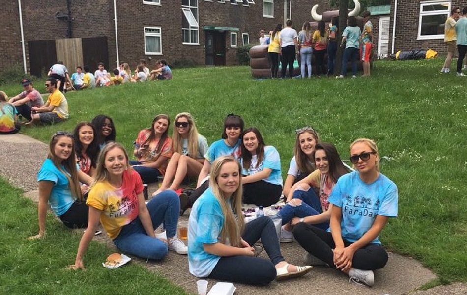 Niamh and her Hall friends sitting on the pavement and grass at Faraday Hall day. 