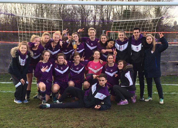 Hannah and her football team in front of a football goalpost. 