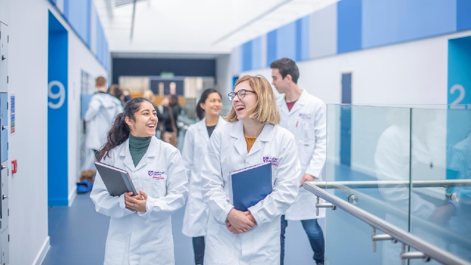 a group of people wearing lab coats walking along a corridor