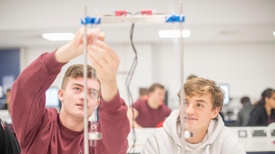 An image showing two male students using equipment in the physics teaching laboratory.