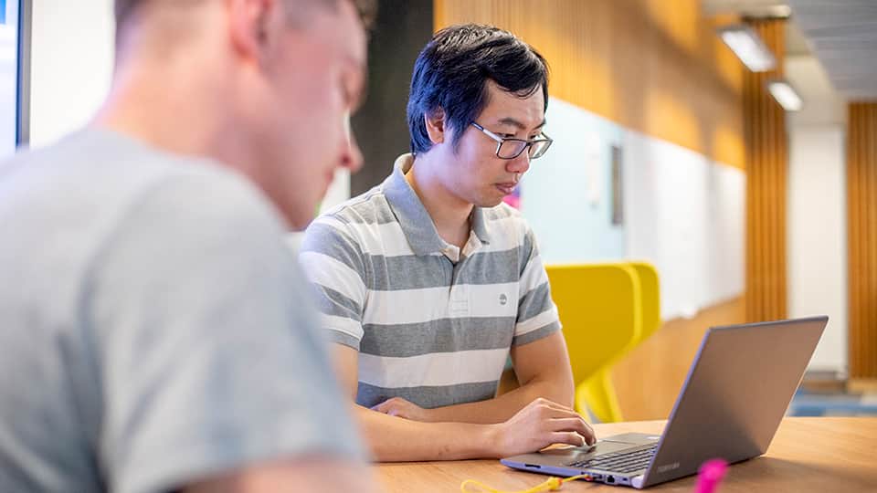 two students using a laptop