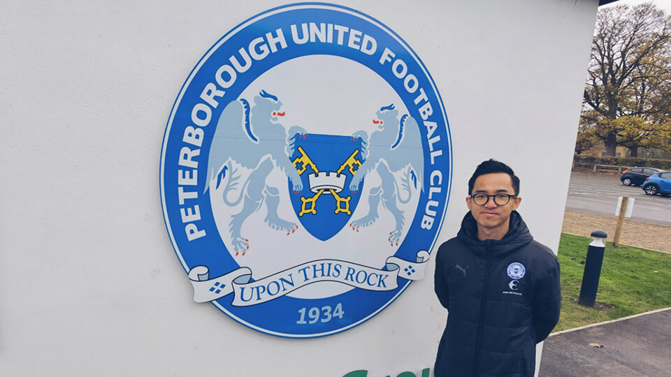 Student standing outside Peterborough Football Club Sign
