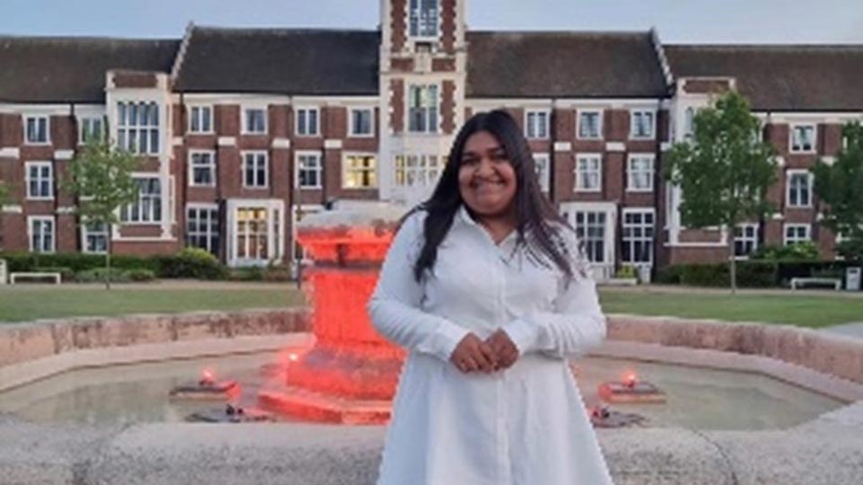 A student standing in front of a fountain