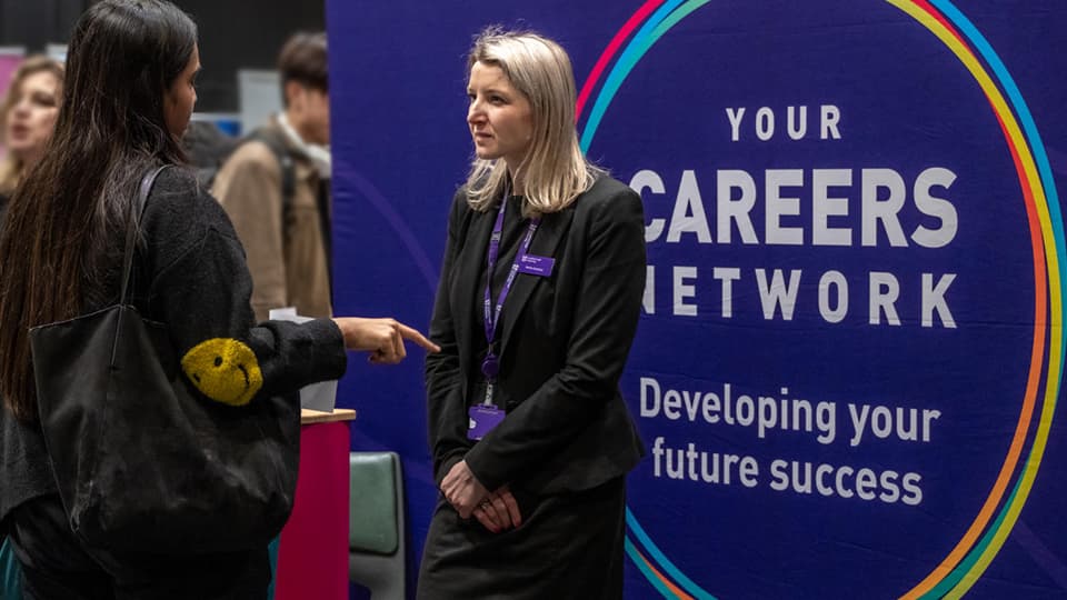 A student talking to a member of staff in front of a sign that says Career Network