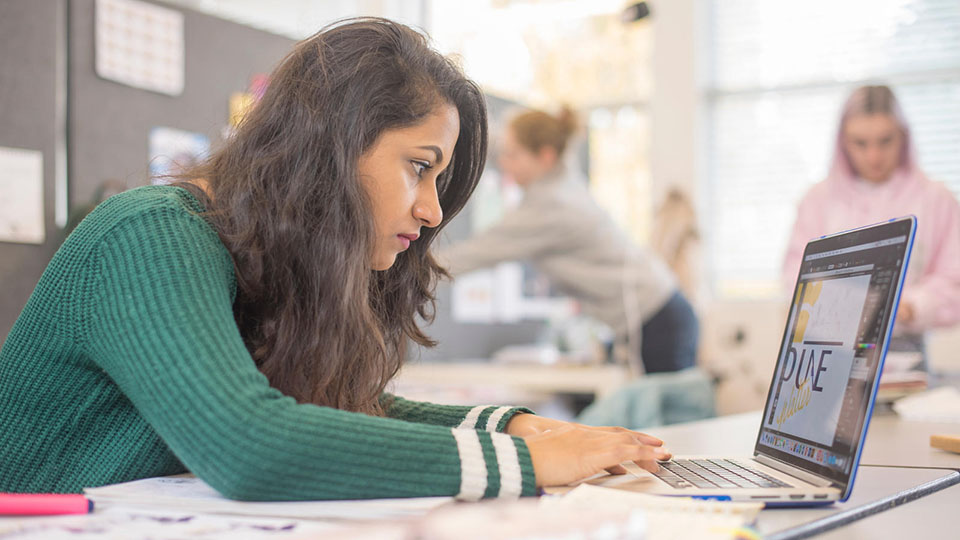 A student looking at a laptop and working
