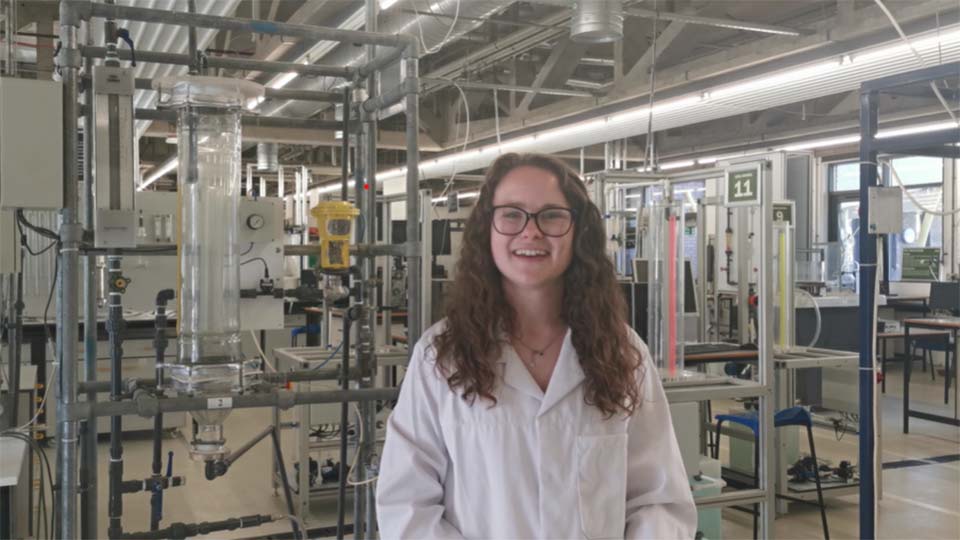 A student in an industrial lab smiling to camera