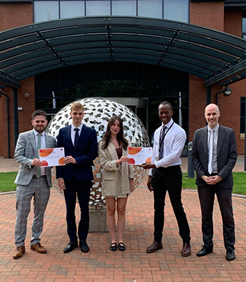 Zoe standing outside the MHR office building and being presented with a certificate.