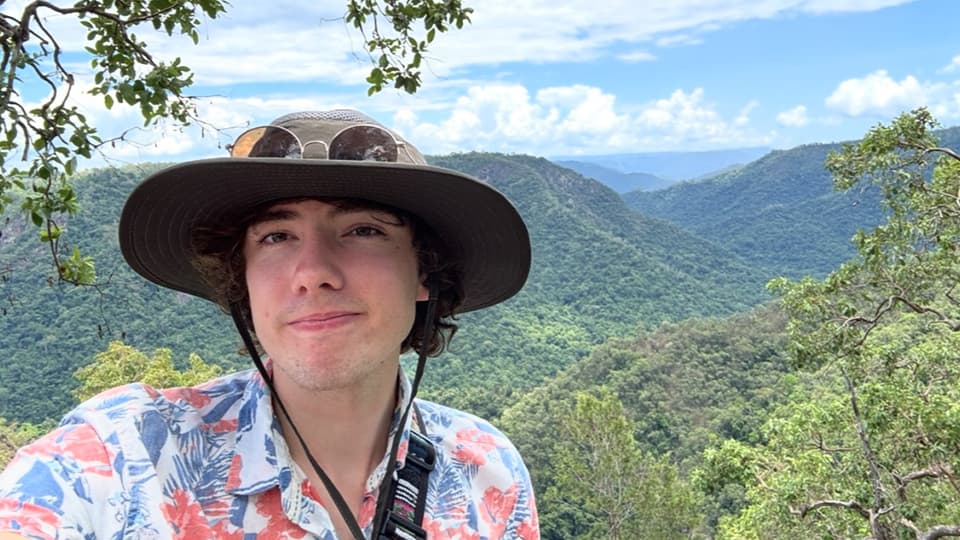 Dominic standing in front of a green landscape in Australia.
