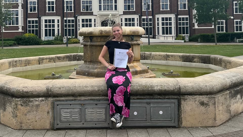 Lily sat in front of a fountain on Loughborough campus
