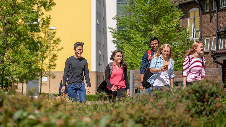 A group of students walking past halls of residence buildings on campus.