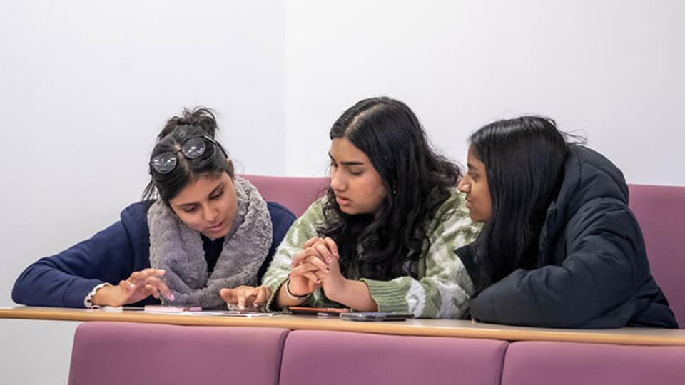Three students sat together in a Personal Best workshop, looking at the same document in front of them