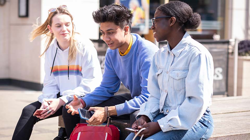 Three students sitting outside in Loughborough Town talking to each other