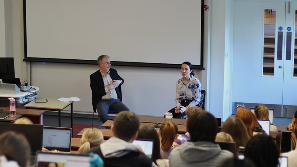 a male and female talking to a group of students in a lecture theatre