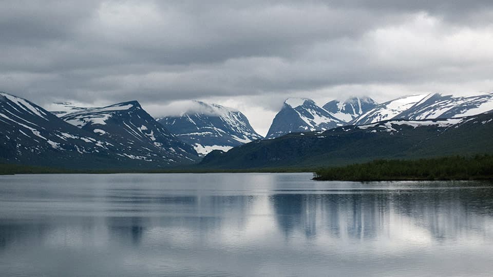 a view across a lake of snow topped mountains in Sweden