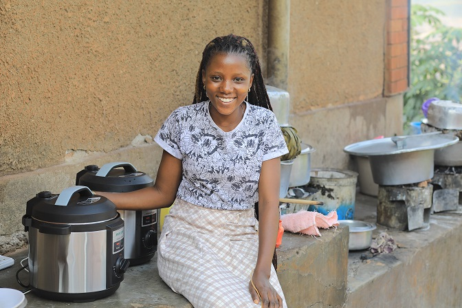 a young femal sat down outside suurounded by cooking equipment