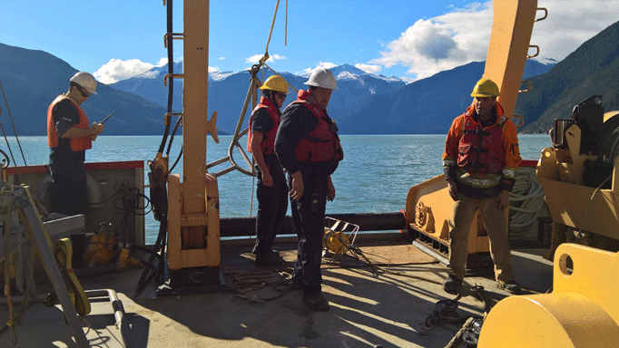 People working on a boat with mountains in the distance