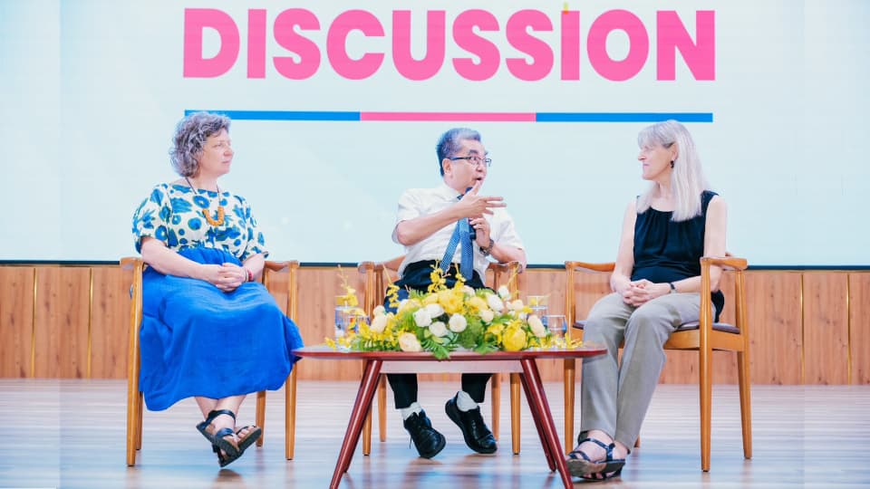 Rosemary Hunter and two other conference participants on a stage under a banner which reads 