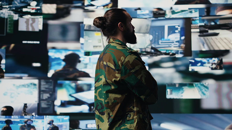 a man looking at a wall of computer screens