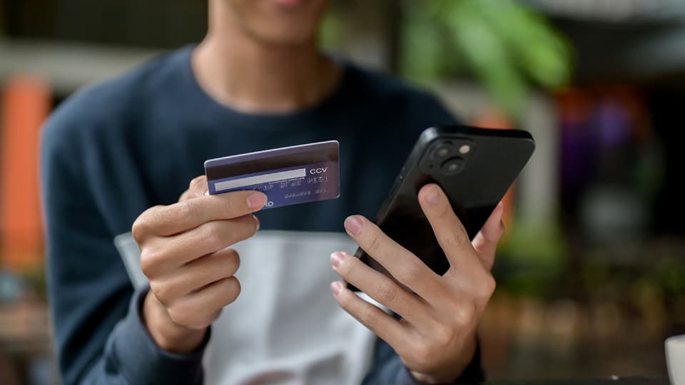 a person holding a bank card in one hand and a mobile phone in another