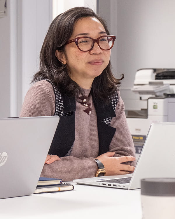 A professional education learner sitting at a desk in front of laptop computers