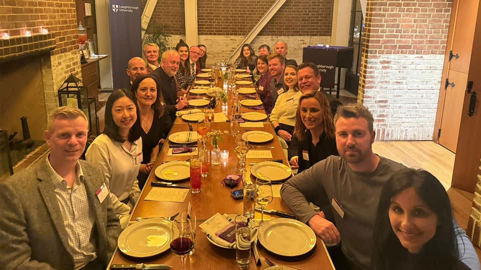 A group of Loughborough alumni, staff, along with Professor Nick Jennings, Vice-Chancellor and President of Loughborough University at a restaurant sitting round a table in Chicago. They are smiling at the camera.