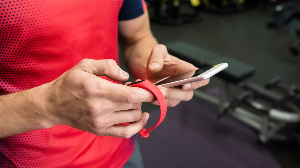 A man checks his fitness tracker in the gym