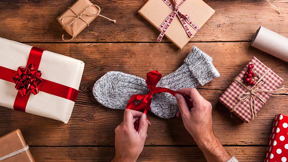 Pictured is man wrapping socks for Christmas.